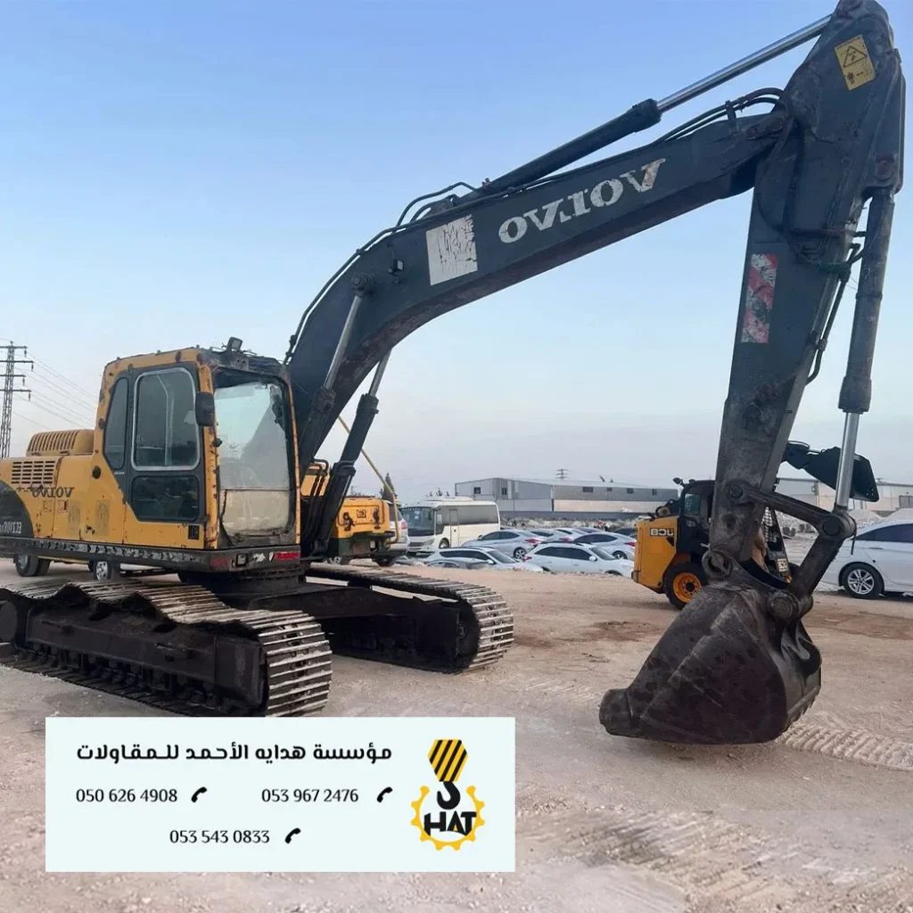 بكلين (حفار) مع إضاءة ساطعة ومشغل يرتدي خوذة الأمان في موقع مظلم